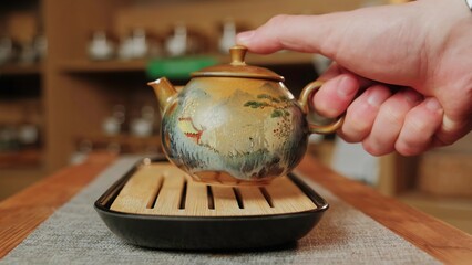 A person pours tea into a teapot on a wooden table, creating tranquility. Media