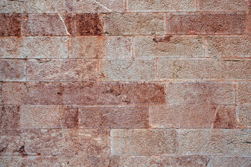 Texture of an old stone wall with a white or slightly rusty tint on certain stones