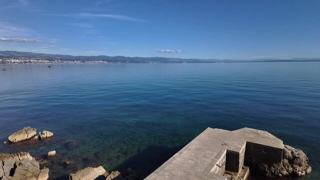 Amazing view from the Lungomare Coastal Promenade near Lovran, Croatia. Rocky coastline of the Adriatic Sea with Rijeka in the background. The famous seaside promenade is more then 100 years old.