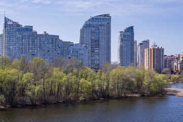 Fototapeta premium Beautiful view of Obolonskaya embankment. View from the bridge to the city embankment and the Dnieper river in Kyiv in spring. Beautiful landscape of the city of Kyiv, Ukraine