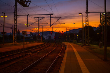 a railway station platform at early morning with red sky
