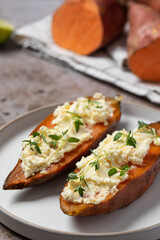 Baked sweet potatoes with creamy cheese topping and fresh herbs. Healthy food