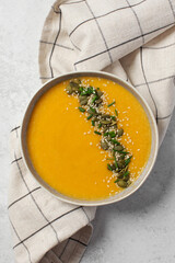 Creamy butternut squash soup with pumpkin seeds and herbs in ceramic bowl. Autumn menu. 
