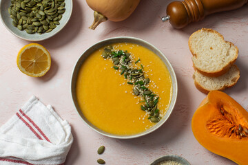 Creamy butternut squash soup with pumpkin seeds and herbs in ceramic bowl. Autumn menu. 