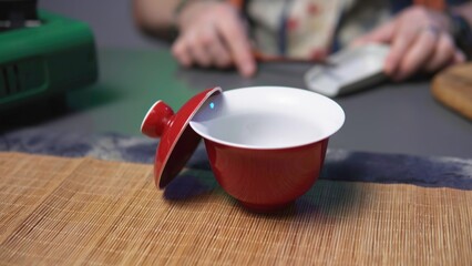 An Artistic Red Tea Cup with a Lid Sits on a Warm Wooden Surface Evoking Calm and Serenity. Media