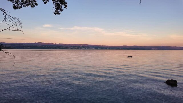 View from the Lungomare Coastal Promenade to the Clinic for Orthopedics Lovran, the city of Rijeka and the Krk Island. Real time beautiful pastel coloured sunset above the Adriatic Sea.