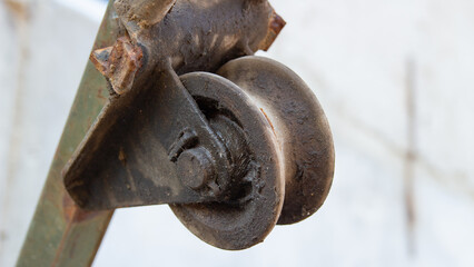 Close-up of a rusty, worn metal roller guide mechanism.