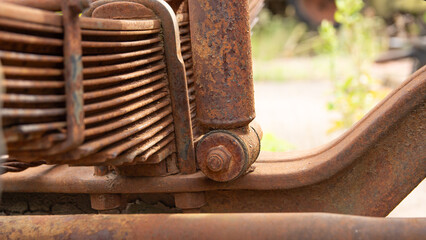 Close-up of heavily rusted leaf springs and a shock absorber, components of a vehicle's suspension system.