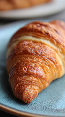 Fototapeta premium closeup of freshly baked croissant on white plate showing golden flaky layers and crisp texture, appetizing bakery food captured in natural lighting with focus on delicious detail and gourmet appearan