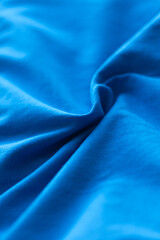Close-up texture of soft blue cotton fabric with flowing folds, offering a vibrant yet calming visual experience, ideal for various backgrounds.