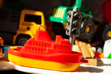 Vibrant toy still life: A red and yellow boat takes center stage among toy trucks and a traffic signal, creating a colorful play scene.