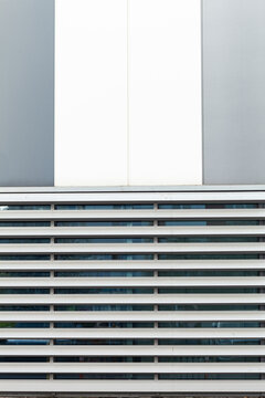 Architectural detail: modern building facade featuring parallel horizontal louvers, clean lines, and geometric color blocking elements.