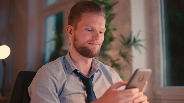 Businessman Sitting at Computer and Checking Smartphone