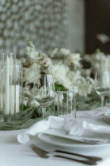 Wedding. Banquet. The chairs and round table for guests, served with cutlery, flowers and crockery and covered with a tablecloth,  green and white theme.