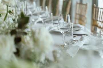 Wedding. Banquet. The chairs and round table for guests, served with cutlery, flowers and crockery and covered with a tablecloth,  green and white theme.