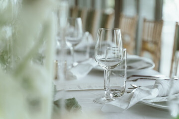 Wedding. Banquet. The chairs and round table for guests, served with cutlery, flowers and crockery and covered with a tablecloth,  green and white theme.