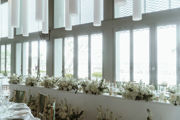 Wedding. Banquet. The chairs and round table for guests, served with cutlery, flowers and crockery and covered with a tablecloth,  green and white theme.