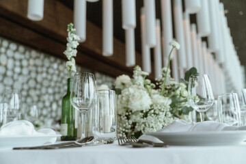 Wedding. Banquet. The chairs and round table for guests, served with cutlery, flowers and crockery and covered with a tablecloth,  green and white theme.