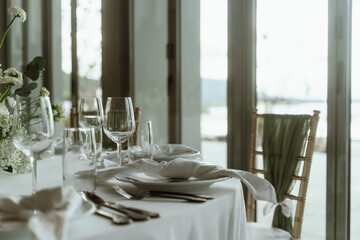 Wedding. Banquet. The chairs and round table for guests, served with cutlery, flowers and crockery and covered with a tablecloth,  green and white theme.