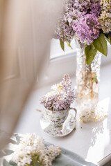 A vibrant lilac bouquet arranged in a floral teacup with delicate purple and white blossoms. This charming setup highlights simplicity, elegance, and springtime freshness.