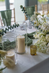 Wedding. Banquet. The chairs and round table for guests, served with cutlery, flowers and crockery and covered with a tablecloth,  green and white theme.
