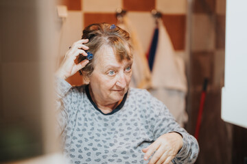 A senior woman in a bright bathroom setting uses hair curlers to style her hair, embracing a moment...