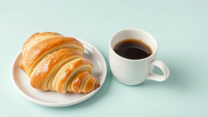 Frisches, goldbraunes Croissant auf weißem Teller neben einer Tasse schwarzen Kaffees auf einem sanft pastellblauen Hintergrund, minimalistisch und appetitlich.