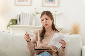 Asian woman feeling unhappy after looking at the bill feels stressed having financial problem, check finances, experiencing lack of money pay for loan, huge taxes, utility rates, get eviction notice