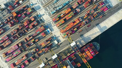 Aerial footage captures container ships sailing into a busy industrial port. Cranes and colorful containers showcase the vibrant global movement of trade and the scale of international shipping.