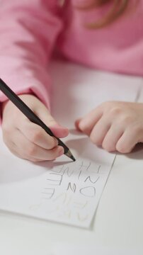 Black English teacher native speaker holds card and little schoolgirl writes digit name on paper at private lesson closeup slow motion
