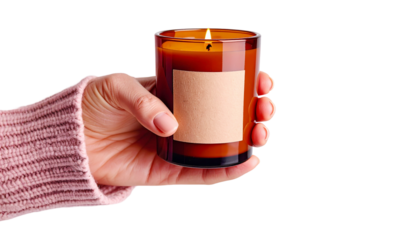 hand holding a burning candle in a clear glass container, a scene of warmth, serenity, and peaceful moments. The flickering flame casts a warm glow.