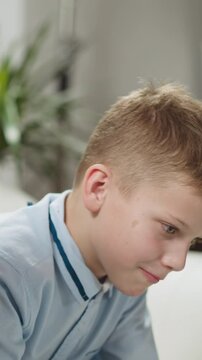 Young black man tutor conducts private English lesson to primary schoolboy at homeschooling with native speaker in living room closeup slow motion