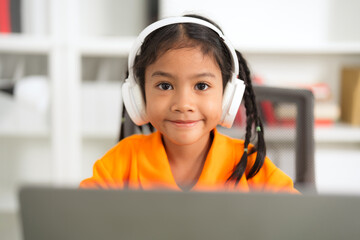 Young girl wearing headphones using laptop for online education