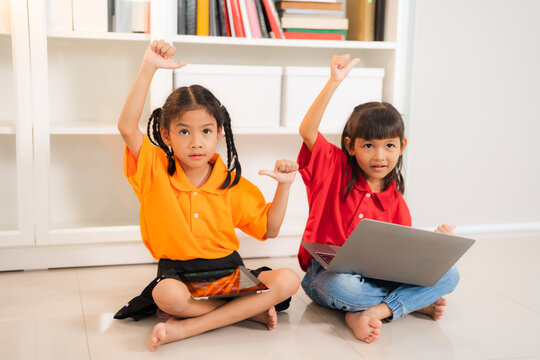 Two asian children using technology and showing thumbs up sign