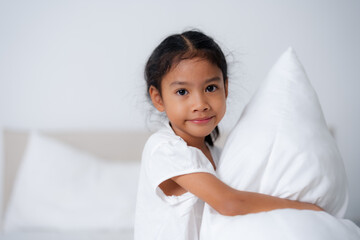 Happy girl hugging pillows on bed in bedroom