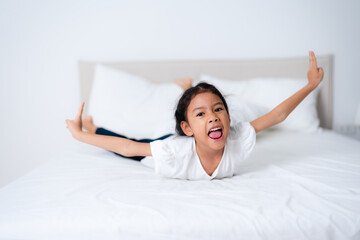 Cute asian girl lying on bed with arms outstretched and pointing up
