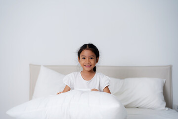 Happy girl hugging pillows on bed in bedroom