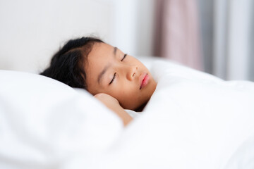 Little girl sleeping peacefully in white bedding