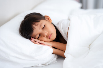 Little girl sleeping peacefully in white bedding