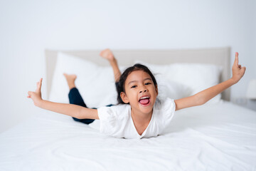 Cute asian girl lying on bed with arms outstretched and pointing up