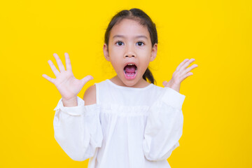Surprised asian girl opening mouth and raising hands on yellow background