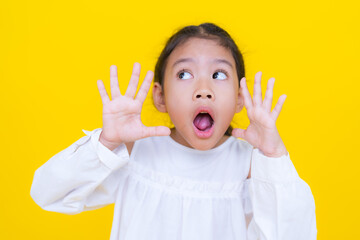 Shocked little girl showing stop sign with her hands on yellow background