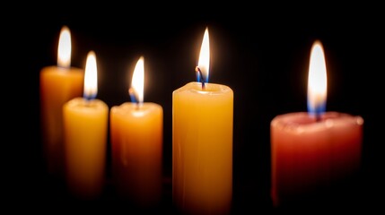 Flames of orange and yellow hues emanate from candles, casting a warm glow in darkness, inviting relaxation and tranquility to the surrounding space