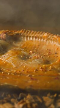Cooking smoked ide fish with seasonings and crispy crust on decayed shavings and charcoals with floating steam in smokehouse macro slow motion