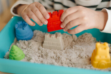 close-up of a child's hands playing on a table with kinetic sand © Karabas