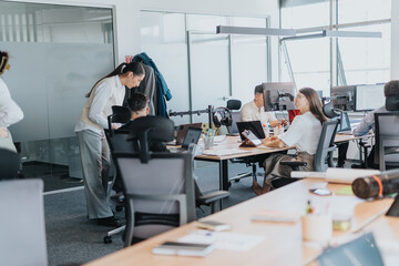 A diverse group of employees working together in a modern office environment, engaging productively with technology and teamwork, embodying collaboration and multiculturalism.