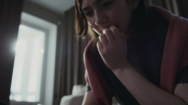 Tilting closeup of hands and face of distressed young Caucasian girl frantically typing messages on smartphone, waiting for answer, biting nails, while communicating with online abusers or fraudster