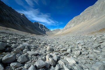 A desolate rocky valley with sharp ridges, stretching under a bright blue sky.