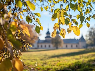 This serene image captures the essence of autumn at a historic country estate. The golden leaves of the trees surrounding the building create a warm, inviting atmosphere, contrasting with the crisp