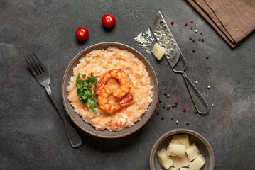 Risotto with shrimps in a bowl on a dark grunge background, top view, flat lay